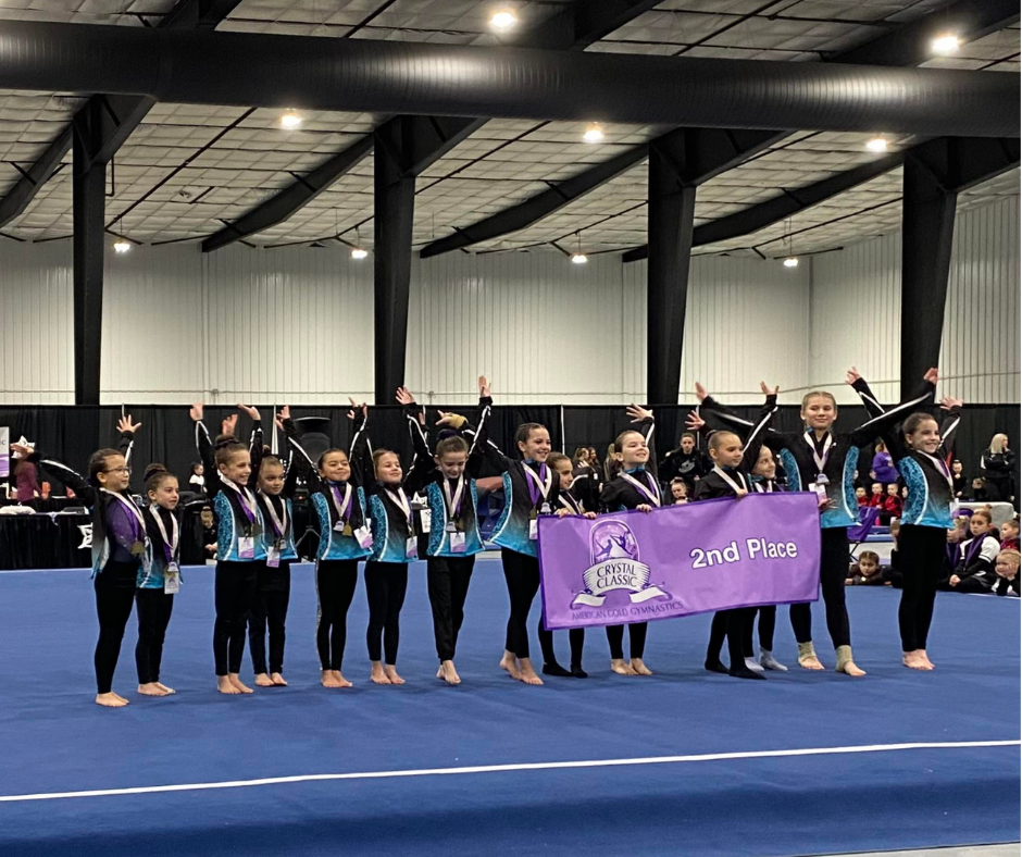 Prairie Reign Gymnastics team wearing medals and holding 2nd place banner